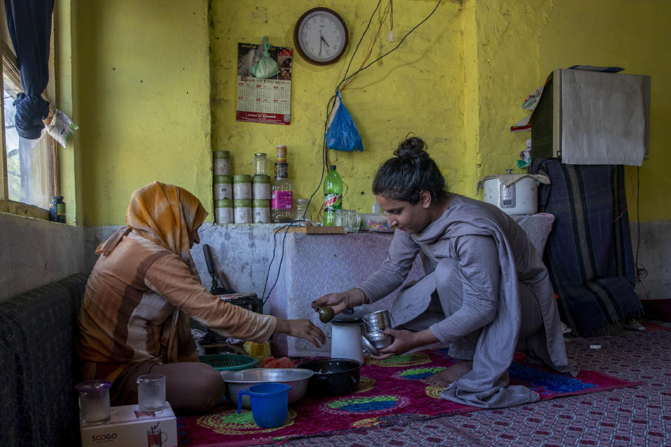 A transgender Kashmiri Khushi Mir, right, helps her mother in the kitchen set up in the corner of a rented room on the outskirts of Srinagar, Indian controlled Kashmir, Friday, June 4, 2021. Until the pandemic, singing and dancing at weddings used to earn Mir enough income to take care of her family. Unable to pay for her rented accommodation, the 19-year-old took a job as a construction worker for 15 days that paid $9.60 a day. Mir has set up a charity, along with four friends, to distribute food kits to members of the transgender community. (AP Photo/ Dar Yasin)