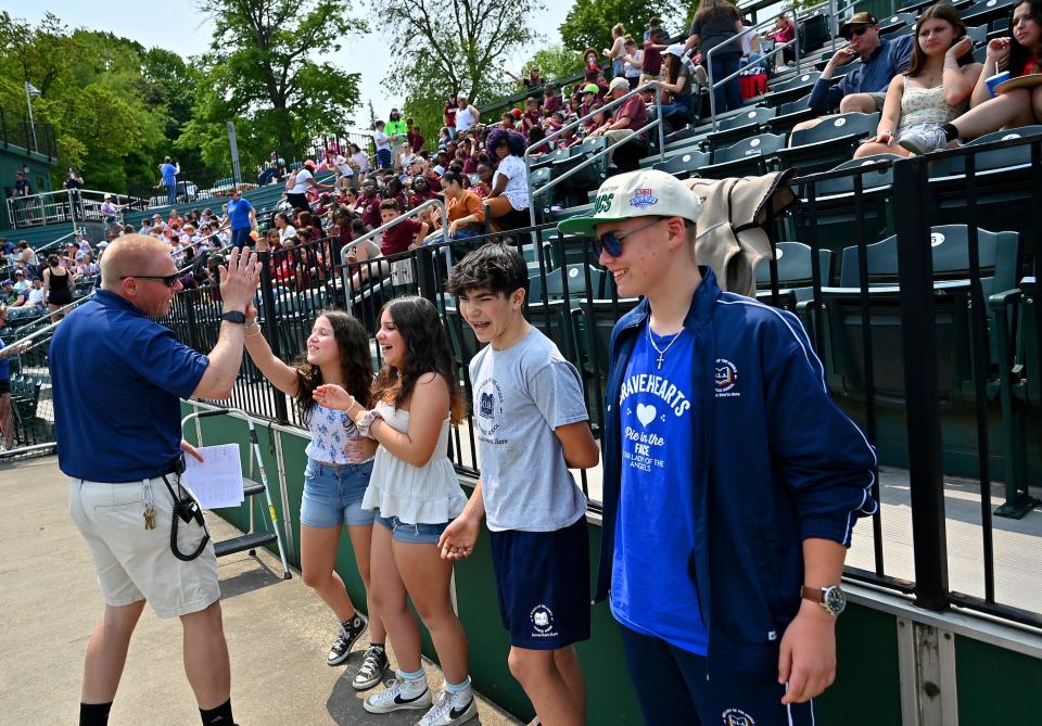 Bravehearts general manager Dave Peterson high-fives school children after asking them math questions during the team's opening game Wednesday at Hanover Insurance Park at Fitton Field.