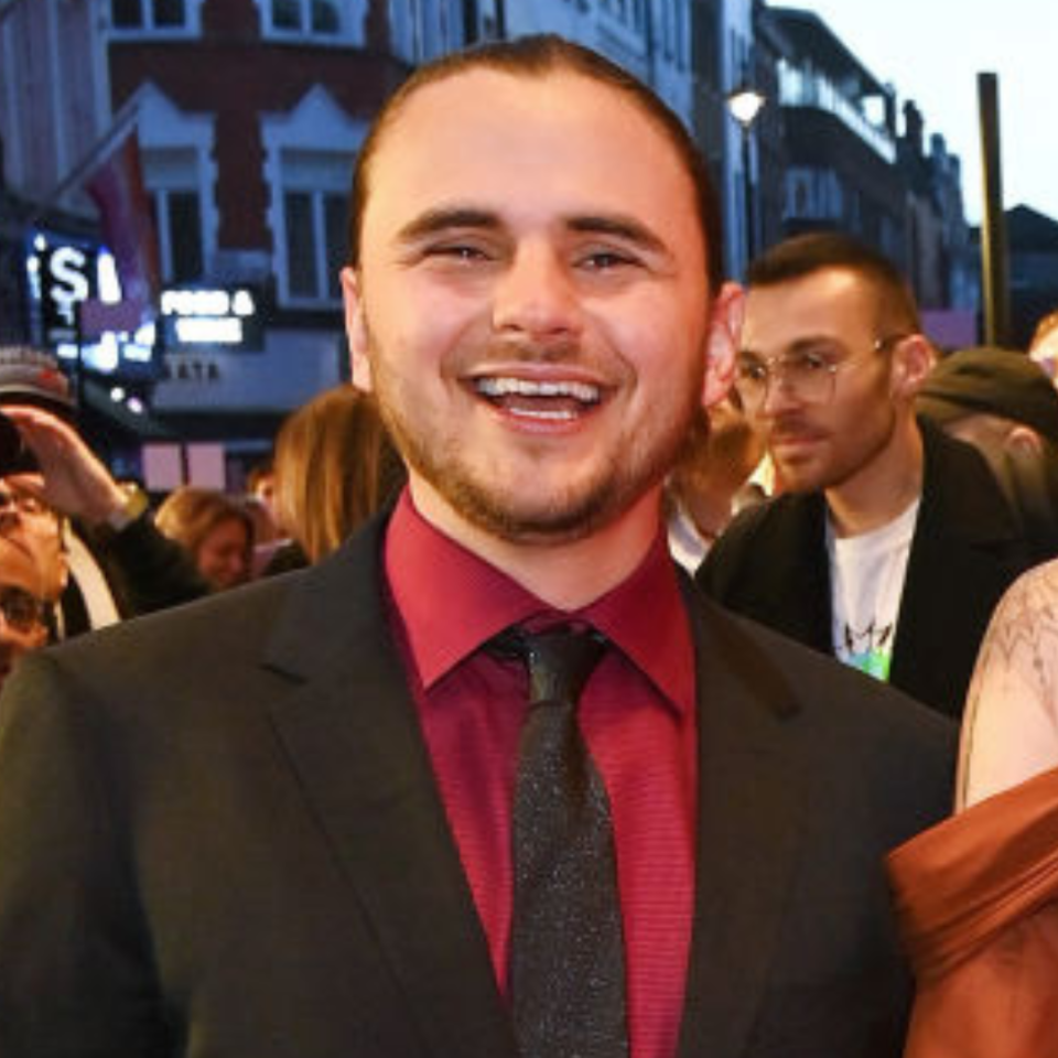 Person in suit with a tie, smiling at a public event