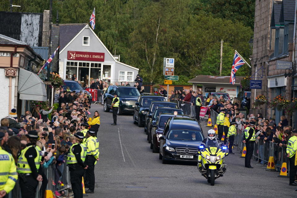 Members of the public line the streets in Ballater, Scotland, as the hearse carrying the coffin of Queen Elizabeth II passes through as it makes its journey to Edinburgh from Balmoral in Scotland, Sunday, Sept. 11, 2022. The Queen's coffin will be transported Sunday on a journey from Balmoral to the Palace of Holyroodhouse in Edinburgh, where it will lie at rest before being moved to London later in the week. (Andrew Milligan/PA via AP)