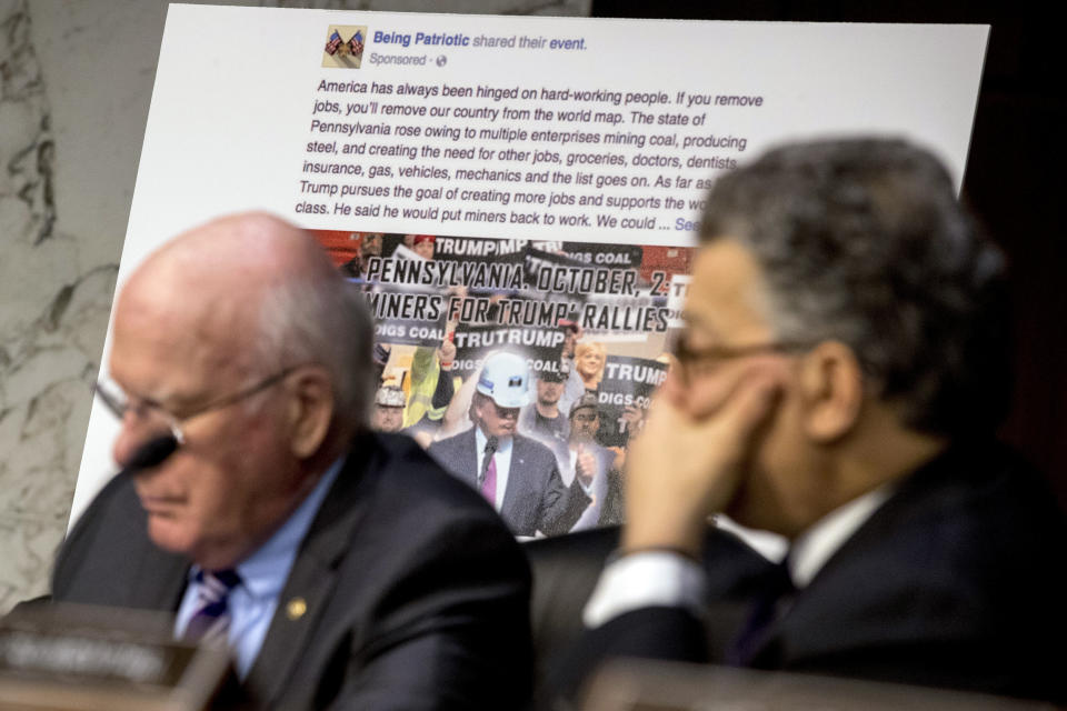 A poster depicting an example of a misleading Internet posting is visible as Sen. Patrick Leahy, D-Vt., left, Sen. Al Franken, D-Minn., listen to testimony. (AP Photo/Andrew Harnik)