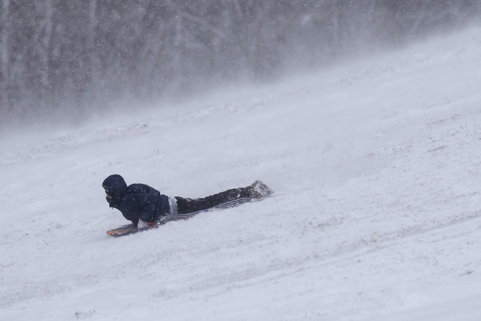 A boy sleds down a snow-covered hill after a winter storm moved through the region Tuesday, Jan. 9, 2024, in Kansas City, Mo. (AP Photo/Charlie Riedel)