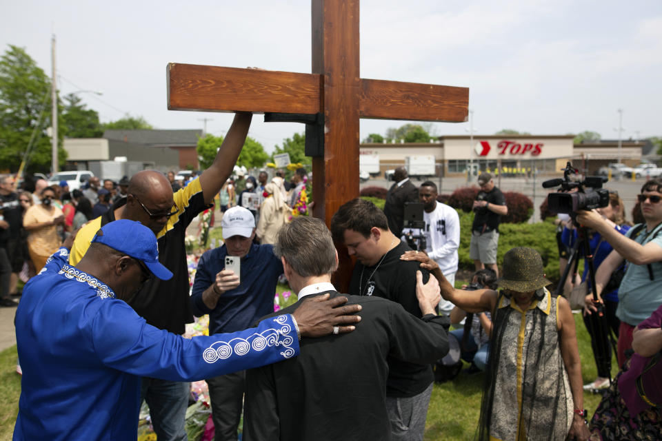 FILE - A group prays at the site of a memorial for the victims of the Buffalo supermarket shooting outside the Tops Friendly Market on Saturday, May 21, 2022, in Buffalo, N.Y. The victims of the mass shooting will be honored with a permanent memorial in the neighborhood. Gov. Kathy Hochul and Mayor Byron Brown on Friday, Oct. 21, 2022, announced the creation of a commission tasked with planning and overseeing construction of a monument in East Buffalo. (AP Photo/Joshua Bessex, File)