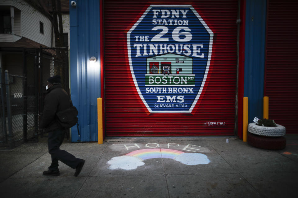 A pedestrian wearing personal protective equipment to protect against the spread of coronavirus, passes EMS station 26, the Tinhouse" Thursday, April 23, 2020 in the Bronx borough of New York. (AP Photo/John Minchillo)