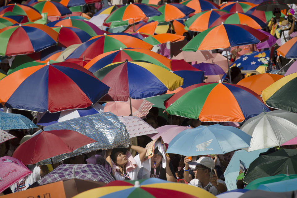 Anti-government protestors shield themselves from the strong midday sun during a rally at Ratchaprasong intersection, Monday, Jan. 13, 2014, in Bangkok, Thailand. Anti-government protesters aiming to shut down central Bangkok took over key intersections Monday, halting much of the traffic into the Thai capital's main business district as part of a months-long campaign to overthrow the democratically elected prime minister. (AP Photo/John Minchillo)