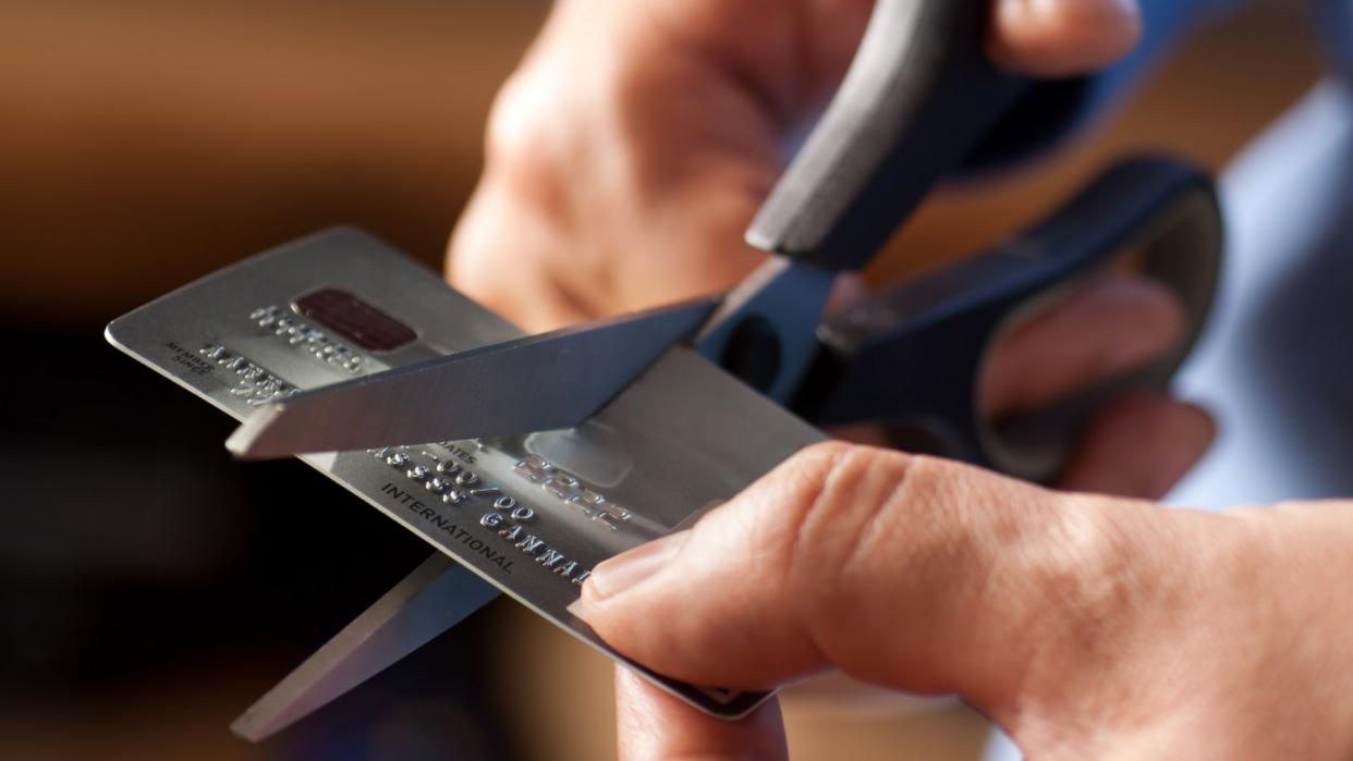 Male hands cutting a credit card with scissors.