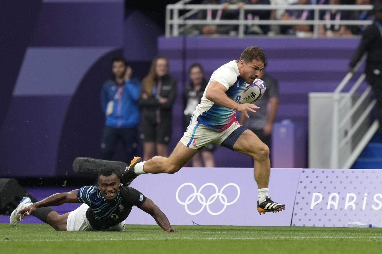 Antoine Dupont of France races clear of Fiji's Waisea Nacuqu to score a try during the men's gold medal Rugby Sevens match between France and Fiji at the 2024 Summer Olympics, in the Stade de France, in Saint-Denis, France, Saturday, July 27, 2024. (AP Photo/Vadim Ghirda)