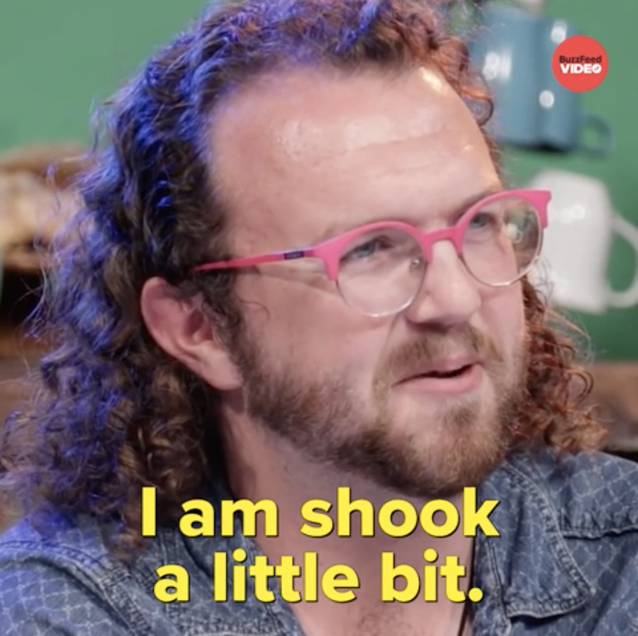 Man with curly hair and pink glasses appears surprised, with caption "I am shook a little bit."