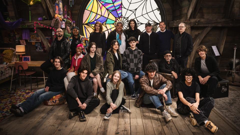 (L to R) Georgie Farmer, Victor Dorobantu, Luyanda Unati Lewis-Nayo, Joy Sunday, Owen Painter, Emma Myers, Billie Piper, Jenna Ortega, Evie Templeton, Luis Guzmán, Isaac Ordonez, Catherine Zeta-Jones, Alfred Gough, Noah Taylor, Miles Millar, Tim Burton, Steve Buscemi, Moosa Mostafa, Hunter Doohan on the set of Wednesday season 2 in Wednesday and Enid's room.