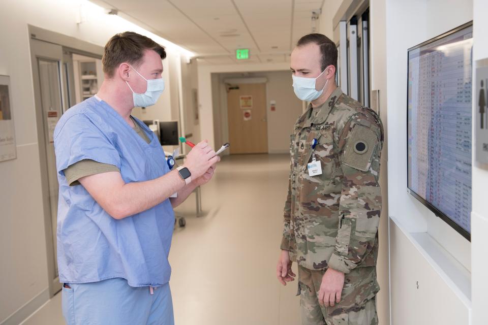 Ohio National Guard Staff Sgt. Zachary Shomper, right, of Columbus, talks to Spc. Daniel Riley of Marion in the Emergency Department at Cleveland Clinic Akron General. Shomper is a supervisor, which is why he is in National Guard uniform. The other Guard personnel wear scrubs with olive-colored T-shirts underneath to help identify them as Guard members.
