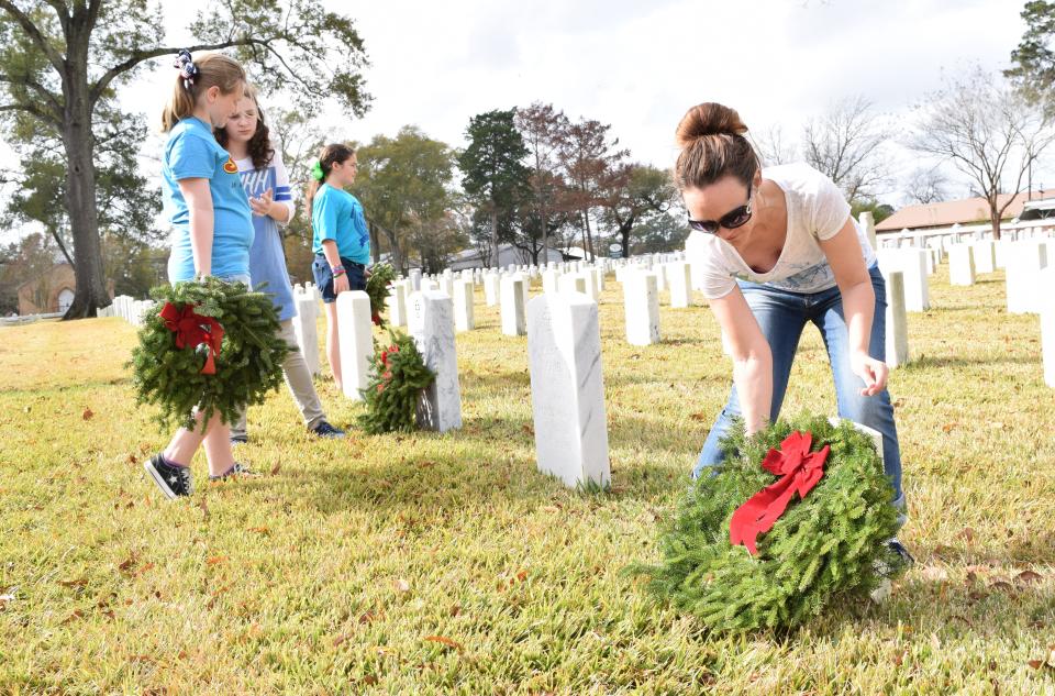 Stephanie Stuckey (far right) lays a wreath on a headstone at Alexandria National Cemetery in Pineville during a past Wreaths Across America event.