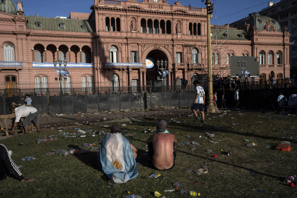 Soccer fans sit on the plaza of the Casa Rosada presidential palace, after waiting for hours for a homecoming parade for the players who won the World Cup title, in Buenos Aires, Argentina, Tuesday, Dec. 20, 2022. A parade to celebrate the Argentine World Cup champions was abruptly cut short Tuesday as millions of people poured onto thoroughfares, highways and overpasses in a chaotic attempt to catch a glimpse of the national team. (AP Photo/Rodrigo Abd)