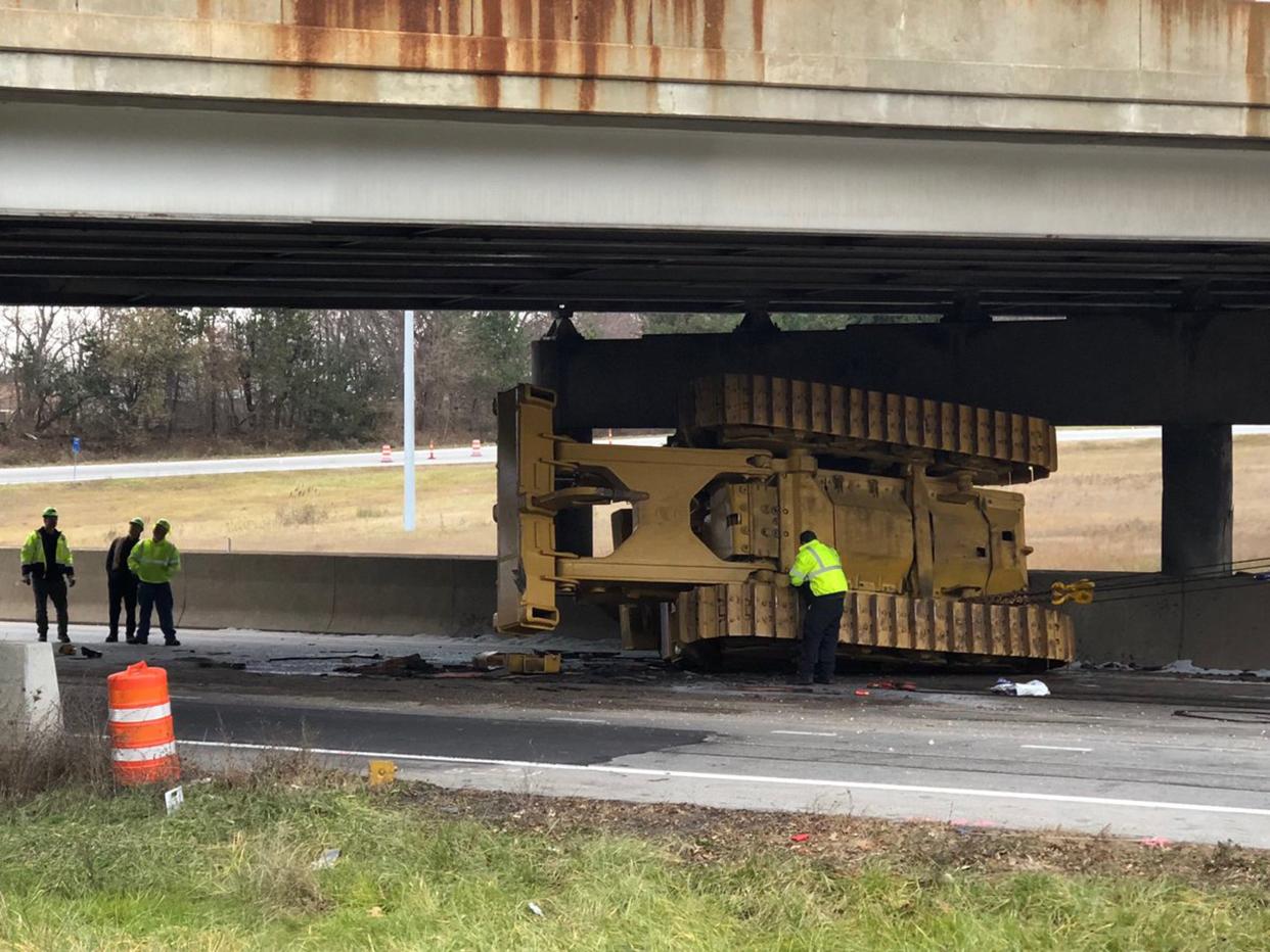 A bulldozer ended up on its side after striking the East Avenue bridge over Interstates 76/77 in Akron when the truck hauling it tried to pass under the bridge early Monday. [Phil Masturzo/Akron Beacon Journal/Ohio.com]