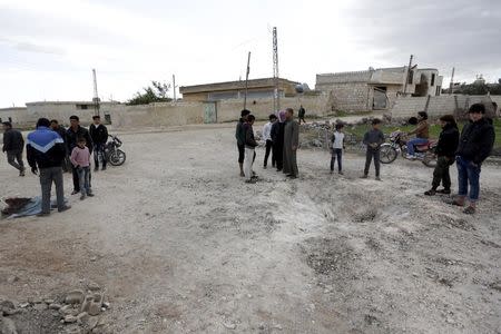 Residents inspect a hole in the ground after a shell fell in the rebel held town of Jarjanaz, southern Idlib countryside, Syria March 5, 2016. REUTERS/Khalil Ashawi