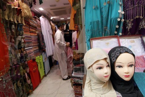 A store employee folds clothes inside a shop at a traditional market in Dubai. To address the rising costs of marriage, the government has ordered that each Emirati man who wants to marry be given $19,000 -- but on condition that it is his first marriage
