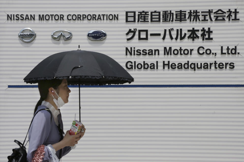 A woman walks past the global headquarters of Nissan Motor Co., Ltd. in Yokohama near Tokyo, Wednesday, May 27, 2020. The Japanese-French auto alliance of Nissan and Renault will be sharing more vehicle parts, technology and models to save costs as the industry struggles to survive the coronavirus pandemic. (AP Photo/Koji Sasahara)