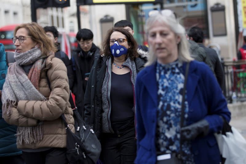 A woman wears a protective mask as she walks on Oxford Street in London