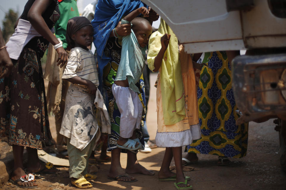 Muslim Children are lifted into a truck that had fallen into a ditch while turning around in Bangui, Central African Republic, Friday, Feb. 14, 2014. A convoy of over 100 vehicles of Muslims fleeing Bangui turned around as MISCA troops, the African Union’s peacekeeping force currently deployed in the Central African Republic, deemed the road out was not secure. (AP Photo/Jerome Delay)