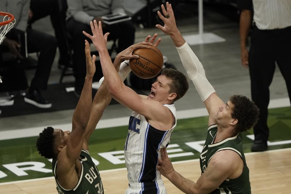 Orlando Magic's Moritz Wagner is fouled as he shoots between Milwaukee Bucks' Giannis Antetokounmpo and Brook Lopez during the second half of an NBA basketball game Tuesday, May 11, 2021, in Milwaukee. (AP Photo/Morry Gash)