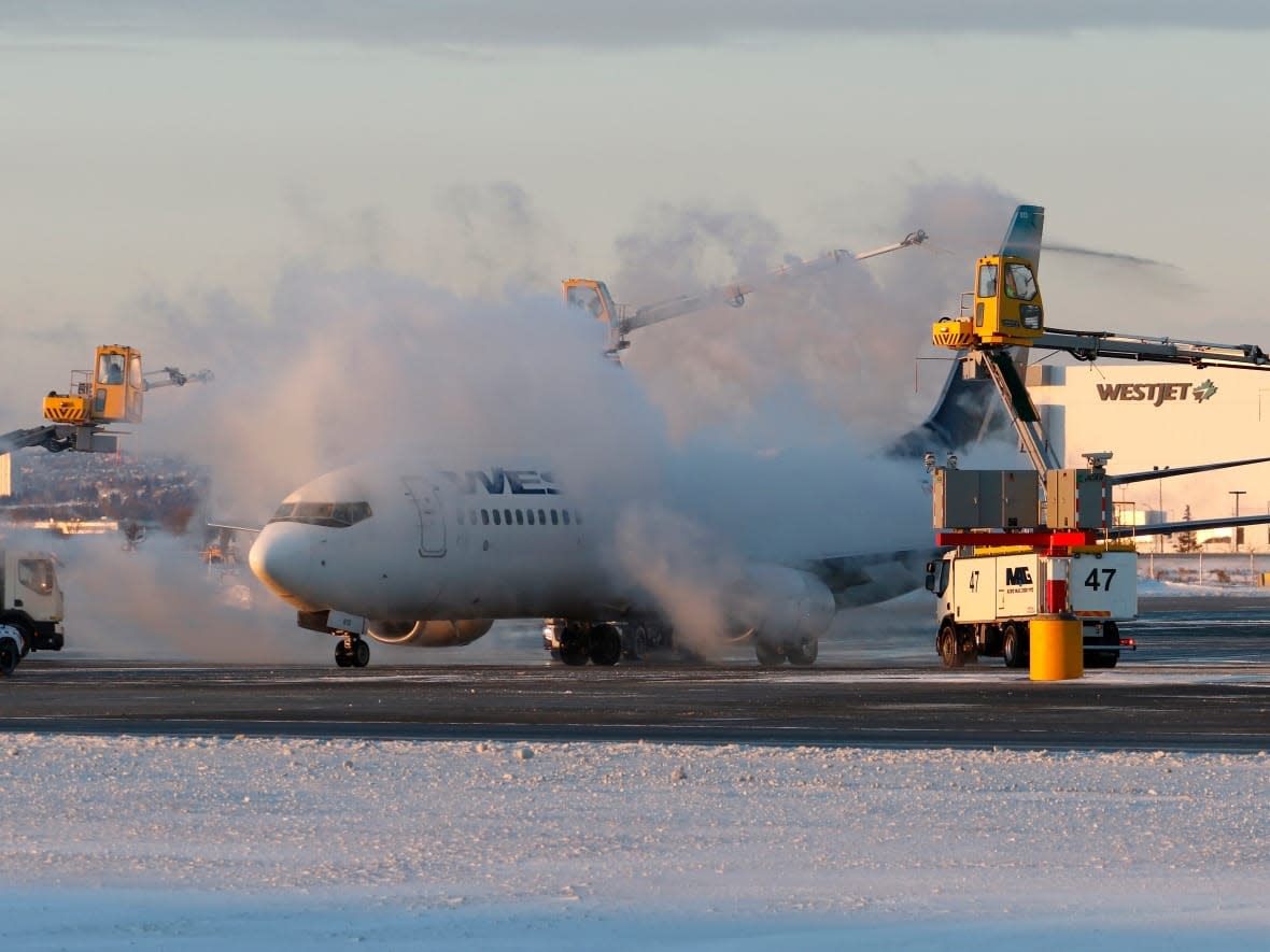 A de-icing station sprays a WestJet Airlines Boeing 737 jetliner prior to its departure at the Calgary International Airport on Monday. (Larry MacDougal/The Canadian Press - image credit)