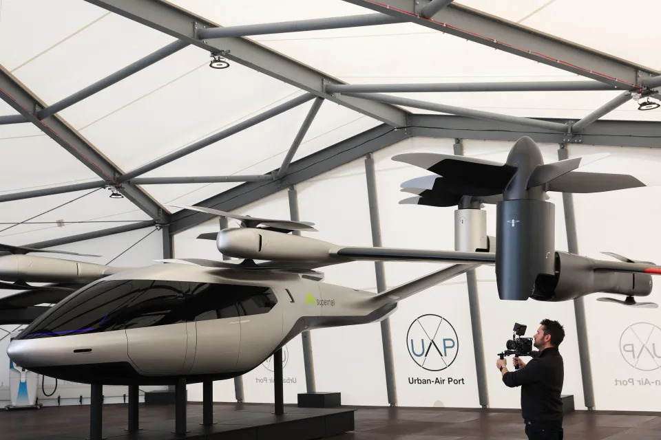 A journalist films a scale model of an electric air vehicle made by Supernal, a company developing a family of electric air vehicles, displayed at Air-One, the world&#39;s first vertiport for flying taxis and autonomous delivery drones at the Urban-Air Port in Coventry on April 25, 2022. (Photo by ADRIAN DENNIS / AFP) (Photo by ADRIAN DENNIS/AFP via Getty Images)