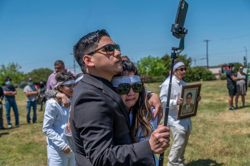 Trang Nguyen is comforted by her brother Jason Le after handing over the live stream camera to him during her father-in-law Dung Tan Nguyen’s funeral in Sacramento on Wednesday, May 6, 2020, during the coronavirus outbreak.”I was crying for three days. It was a lot of stress. I would have hired a photographer and videographer,” said Nguyen. At right her husband Bao Nguyen holds a picture of his father.