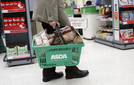 A man carries a shopping basket in an Asda store in northwest London, Britain August 18, 2015. REUTERS/Suzanne Plunkett