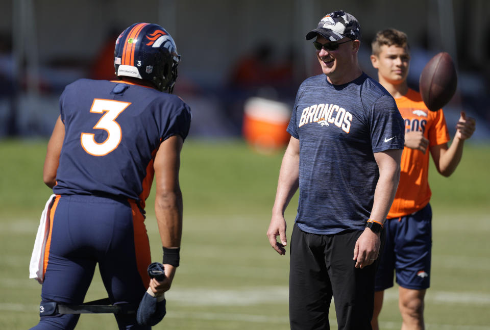 Denver Broncos head coach Nathaniel Hackett, front right, jokes with quarterback Russell Wilson (3) during an NFL football training camp session at the team's headquarters Monday, Aug. 8, 2022, in Centennial, Colo. (AP Photo/David Zalubowski)