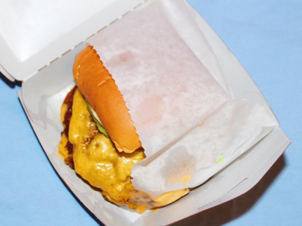 shake shack double cheeseburger in paper wrapping on blue background