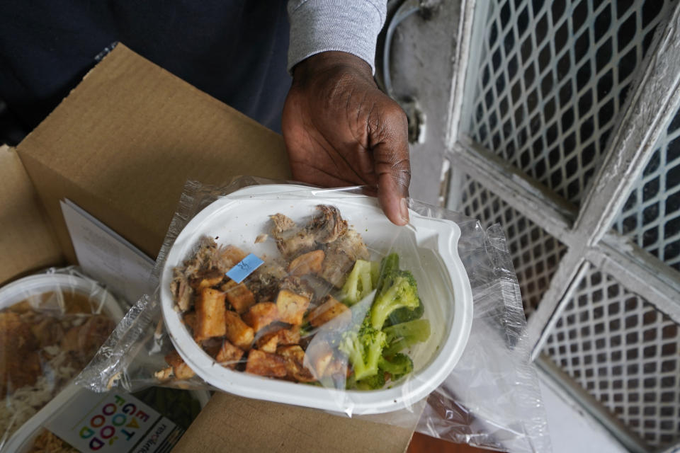 Jackie Robinson shows the contents of meal boxes he received that were delivered by Revolution Foods in New Orleans on Thursday, Feb. 11, 2021. Robinson, a 66-year-old retired cook who once worked at a French Quarter restaurant in New Orleans, struggled to get by on his Social Security benefits before the pandemic, occasionally visiting a food pantry. But over the summer he signed up for a city-run delivery program and now gets two meals a day, seven days a week. "Things were getting kind of tough, a little rough and ... I needed a little extra assistance," he said. (AP Photo/Gerald Herbert)