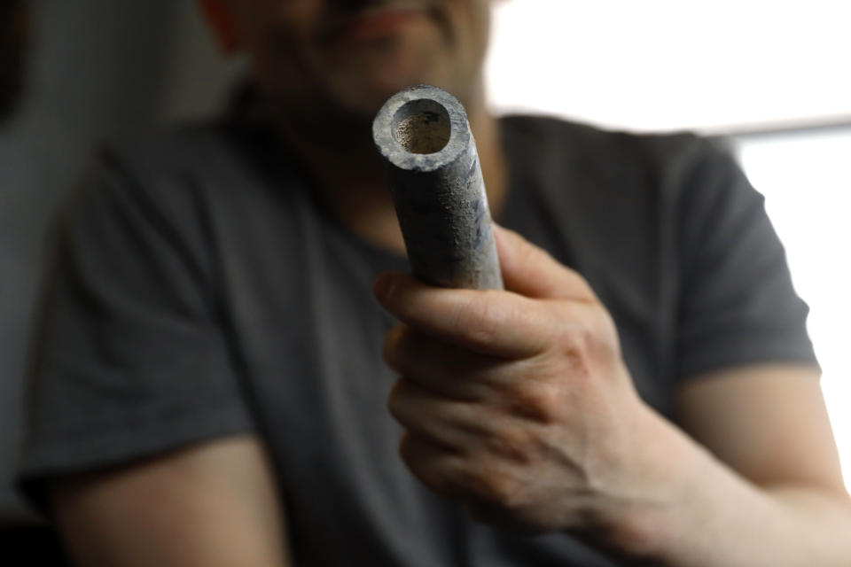 Troy Hernandez, an environmental justice activist with Pilsen Environmental Rights and Reform Organization shows a piece of lead pipe obtained from his residence during his home renovation, Friday, April 9, 2021 in Chicago's Pilsen neighborhood. Hernandez recently spent $15,000 to replace the lead service lines bringing water into his home. (AP Photo/Shafkat Anowar)