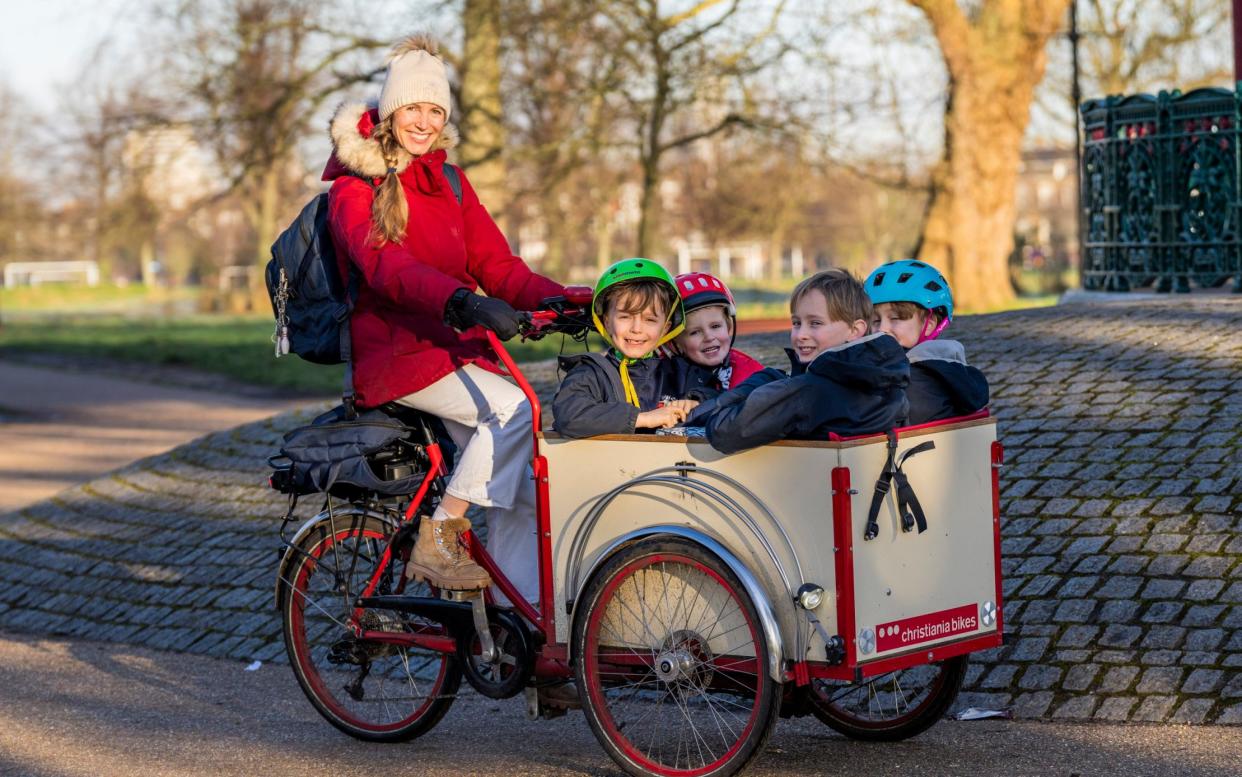 Anna Tyzack rides an electric cargo bike carrying her four children