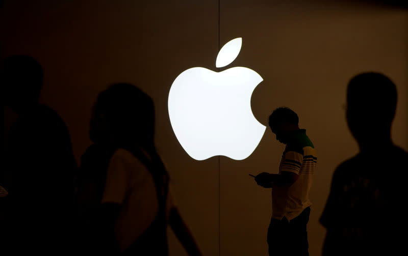 FILE PHOTO: A man looks at the screen of his mobile phone in front of an Apple logo outside its store in Shanghai, China on July 30, 2017. REUTERS/Aly Song/File Photo