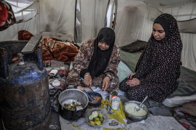 An elderly displaced Palestinian woman prepares food in her tent at a temporary camp in the southern Gaza Strip city of Rafah. Abed Rahim Khatib/dpa