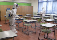 Workers wearing protective gear disinfect as a precaution against the new coronavirus in a class at a high school in Busan, South Korea, Saturday, May 30, 2020. (Jo Jung-ho/Yonhap via AP)