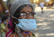 An Indian tribal woman wearing a face mask as a precaution against the coronavirus stands in front of a hospital for a general checkup in Hyderabad, India, Saturday, Dec. 5, 2020. India is second behind the U.S. in total coronavirus cases. Its recovery rate is nearing 94%. (AP Photo/Mahesh Kumar A.)