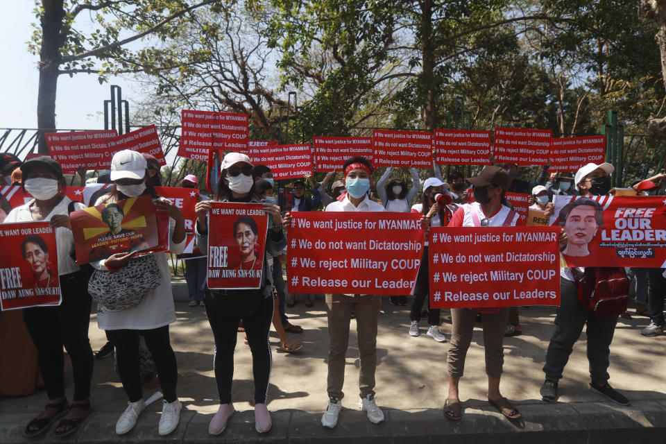 Anti-coup protesters hold placards and posters with an image of deposed Myanmar leader Aung San Suu Kyi as they gather outside the U.N. Information Office in Yangon, Myanmar, Sunday, Feb. 14, 2021. Vast numbers of people all over Myanmar have flouted orders against demonstrations to march again in protest against the military takeover that ousted the elected government of Suu Kyi. (AP Photo)