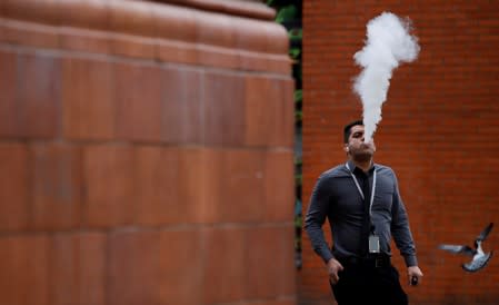 FILE PHOTO: A man vapes outside an office block in Manchester, Britain