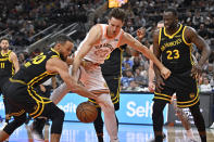 San Antonio Spurs' Zach Collins, center, tangles with Golden State Warriors' Stephen Curry (30) and Draymond Green, right, during the first half of an NBA basketball game Sunday, March 31, 2024, in San Antonio. (AP Photo/Darren Abate)