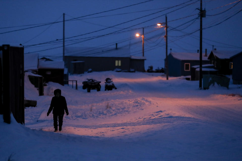 FILE - In this Jan. 20, 2020, file photo, a woman walks before dawn in Toksook Bay, Alaska, a mostly Yuip'ik village on the edge of the Bering Sea. A federal judge has ruled that Alaska Native corporations are eligible for a share of coronavirus relief funding set aside for tribes. Congress included $8 million for tribes in a relief package approved earlier this year. (AP Photo/Gregory Bull, File)