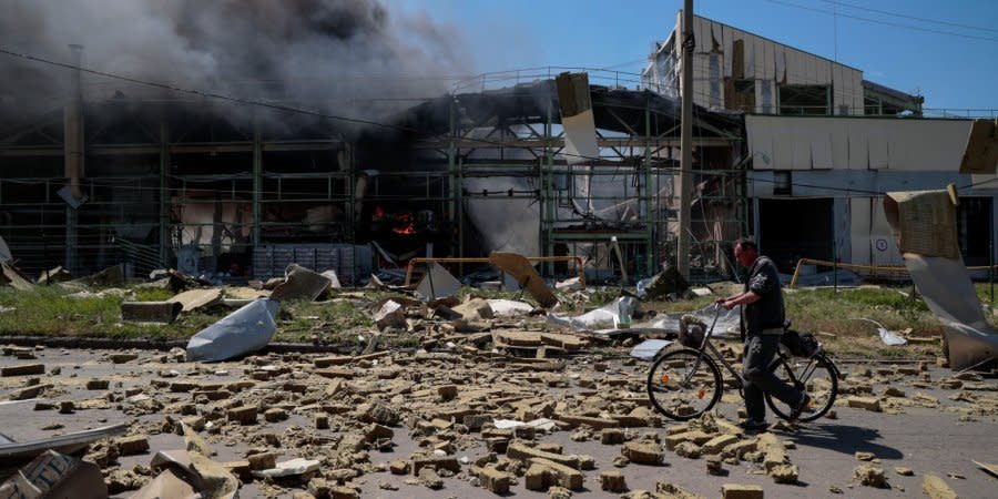 A resident of Bakhmut in Donetsk Oblast passes a warehouse destroyed by Russian shelling