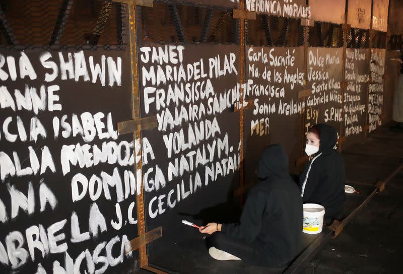 Women paint the names of victims of femicide in Mexico on fences placed outside the National Palace ahead of a Women's Day protest, in Mexico City