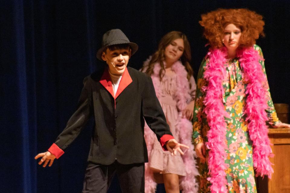 Dominic Falconer portrays Rooster as Gracie McGeehen, as Miss Hannigan, and Corie Horning, as Lily, look on during an Alliance Middle School performance of "Annie Jr."