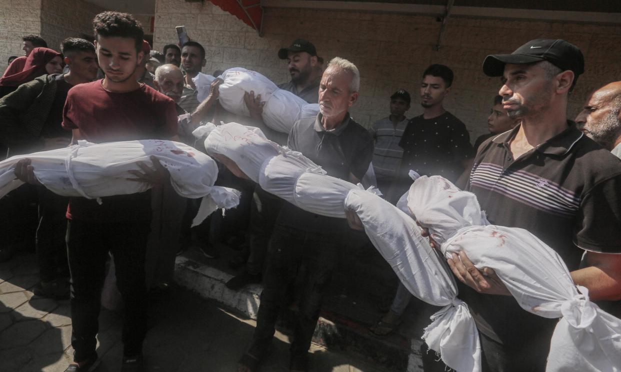 <span>Palestinians holding shrouded bodies at Al-Aqsa hospital in Deir al-Balah, Gaza, on 10 July 2024.</span><span>Photograph: APAImages/REX/Shutterstock</span>