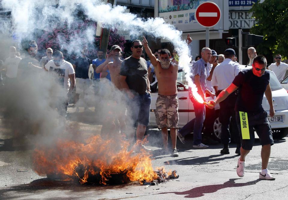 Taxi drivers on strike burn tyres during a national protest against car-sharing service Uber in Marseille, France, June 25, 2015. (REUTERS/Jean-Paul Pelissier)