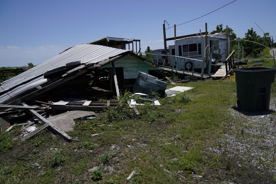 A destroyed home from Hurricane Ida is seen next to a mobile trailer on Isle de Jean Charles, La., Thursday, May 26, 2022, nine months after the hurricane ravaged the bayou communities of southern Louisiana. (AP Photo/Gerald Herbert)