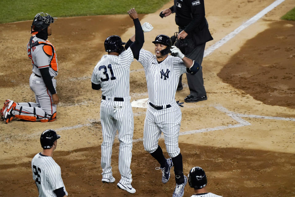 Baltimore Orioles catcher Pedro Severino, left, watches the outfield as New York Yankees designated hitter Giancarlo Stanton, right, celebrates with teammate Aaron Hicks, left, after Stanton hit a grand slam during the fifth inning of a baseball game, Monday, April 5, 2021, at Yankee Stadium in New York. (AP Photo/Kathy Willens)