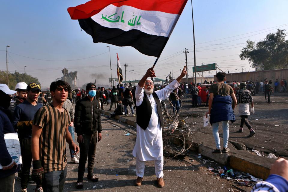 A protester waves the national flag during clashes with security forces in central Baghdad, Iraq, Monday, Jan. 20, 2020. Iraqi security forces also used live rounds, wounding over a dozen protesters, medical and security officials said, in continuing violence as anti-government demonstrators make a push to revive their movement in Baghdad and the southern provinces. (AP Photo/Khalid Mohammed)