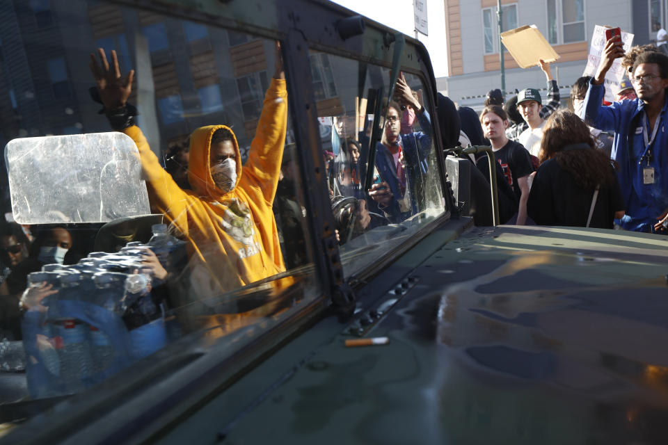 Protesters stand near a Minnesota National Guard vehicle Friday, May 29, 2020, in Minneapolis. Protests continued following the death of George Floyd, who died after being restrained by Minneapolis police officers on Memorial Day. (AP Photo/John Minchillo)