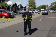 A Phoenix police officer connects crime scene tape together outside the scene of a deadly shooting early Monday, March 30, 2020, in Phoenix. Phoenix police say one of their commanders was killed and two other officers were wounded as they responded to a domestic dispute. Authorities say Cmdr. Greg Carnicle and officers were called to a home in the northern part of Phoenix Sunday night over a roommate dispute when the suspect refused to cooperate and shot them. The suspect was not identified and was pronounced dead at the scene. (AP Photo/Matt York)